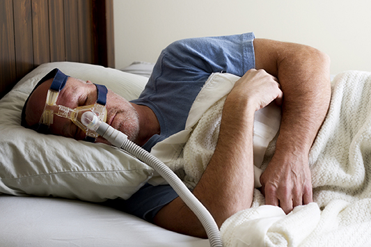 Man wearing continuous positive airway pressure (CPAP) machine to treat sleep apnea
