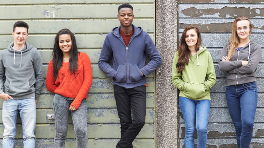Five teenagers leaning against a wall