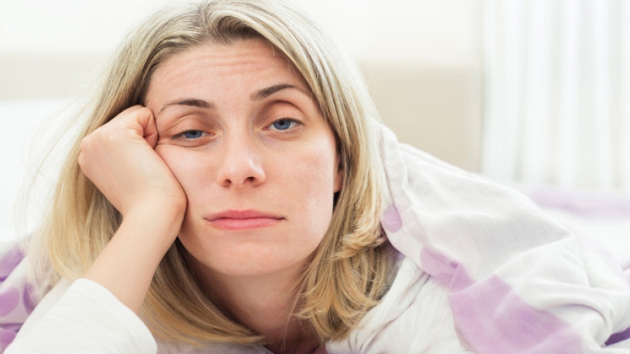 A drowsy woman holding her head up with her right hand.