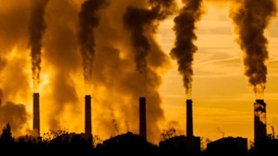 A row of smoke stacks emitting smoke.
