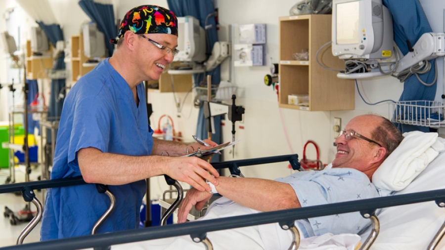 A medical practitioner is tending to a patient in a hospital bed