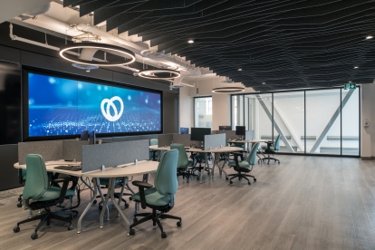 The large screen positioned at the front of this cluster of shared workstations serves as a visual conduit, enabling team members to collaborate seamlessly and visualize complex data.