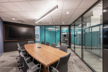 A boardroom featuring glass walls and a large screen provides an unobstructed and immersive environment for effective meetings.