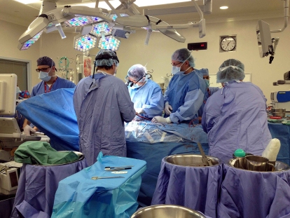 In 2012, Dr. Marc Ruel (back facing camera) performs one of three heart transplants in 24-hours. To the left, the donor heart rests in a bucket covered by a green towel. A typical transplant operation can take six or more hours on average.