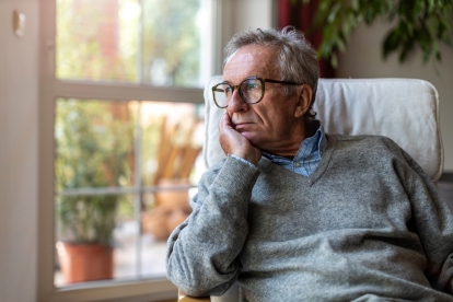 man looking out of window at home