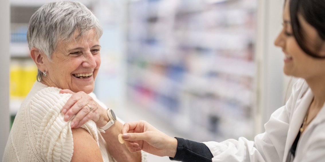 Woman receiving arm vaccination from healthcare professional in pharmacy