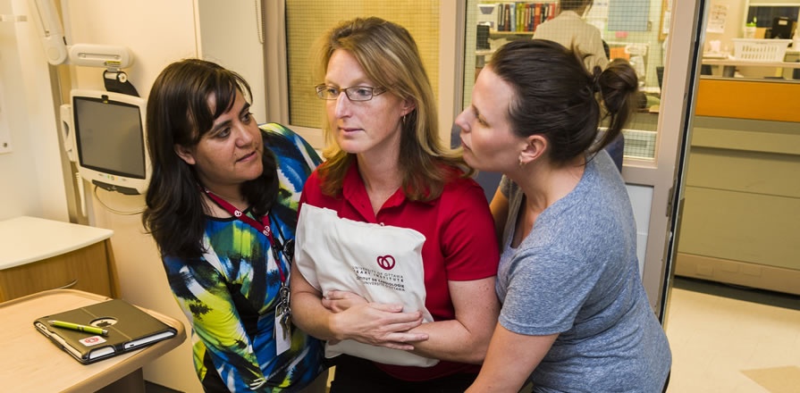 Heart Institute occupational therapist Linda Varas Brulé (left) offers skills training for caregivers, such as how to safely help a patient stand up without risking injury to them or their caregiver.