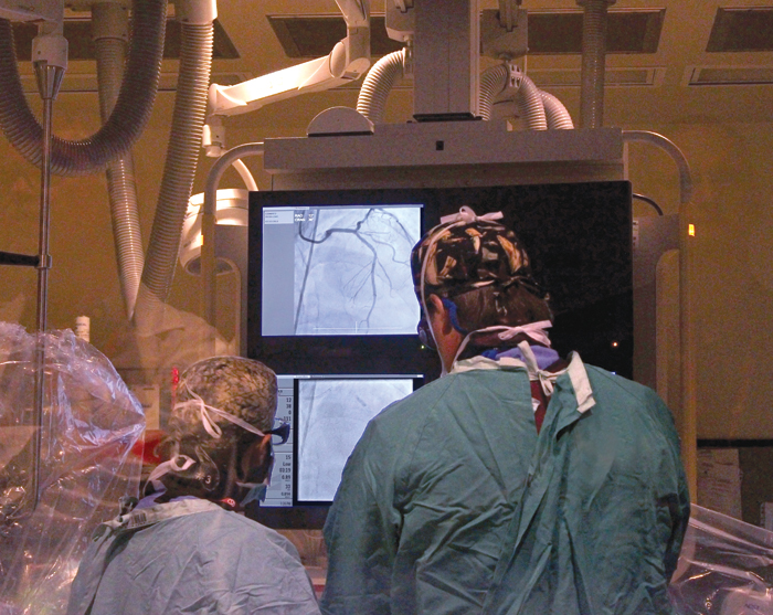 Participants in the ENACT-AMI trial undergo cardiac catheterization in which genetically altered stem cells, unaltered stem cells or a placebo is injected directly into the coronary artery near the damaged tissue. Heart Institute cardiologist Dr. Sandy Dick (right) performs the procedure on the trial’s first participant.