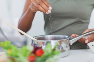 A woman adding salt to a dish